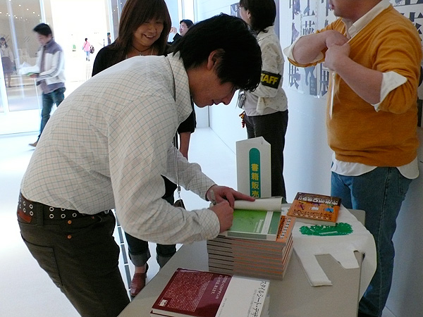 写真：書籍即売ブースでサインする益子貴寛さん